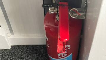 Un extincteur rouge est placé devant une porte blanche.