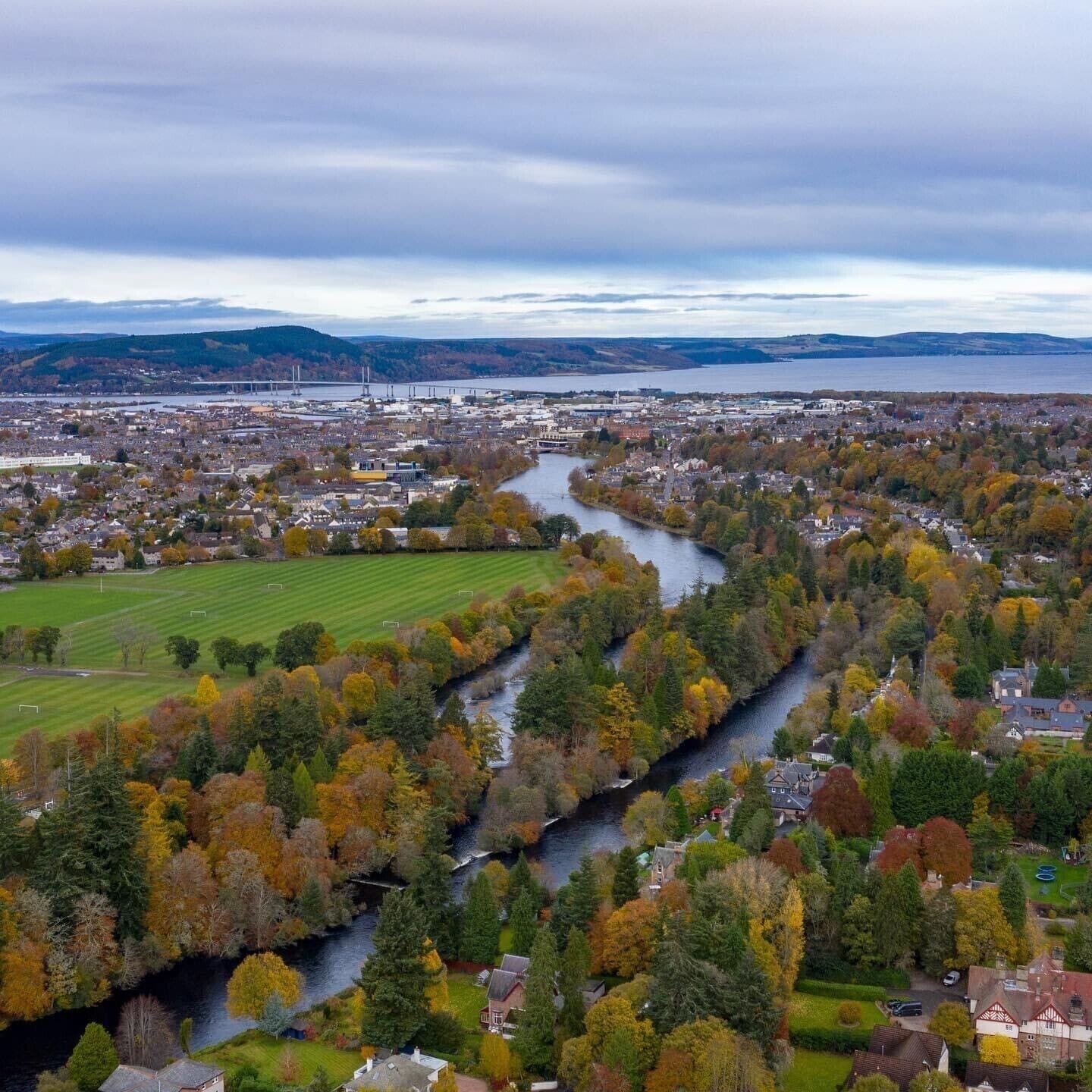 Ilmakuva kaupungista, jonka läpi virtaa joki. Kaupungin ympärillä on syksyn väreissä loistavia puita, ja kauempana näkyy silta.
