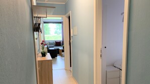 En smal hall med en träbeklädd disk och ett litet bord med en vas med blommor.