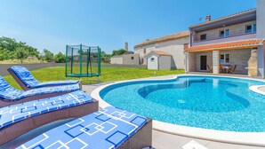 A swimming pool with lounge chairs, a covered patio, and a house with a tiled roof. - Cozy home in Bratulici (Bratulici)