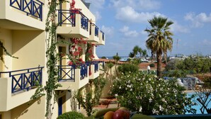 Un hôtel doté de balcons ornés de fleurs et de plantes grimpantes, d’un espace piscine et offrant une vue sur la mer.