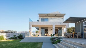 Une maison moderne à deux étages dotée d’un patio, d’un espace salon extérieur et d’un hamac.