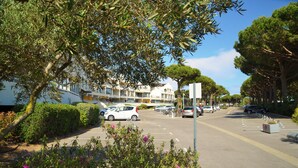 A street lined with trees and parked cars, with a building featuring balconies in the background. - Studio for 2 Adults, Sea & Garden View (Le Grau-du-Roi)