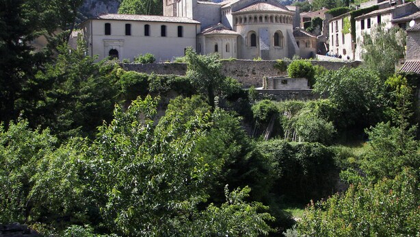A historic building complex with multiple structures, surrounded by lush greenery and mountains in the background. - Studio for 2 Adults, Sea & Garden View (Le Grau-du-Roi)