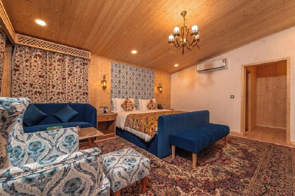 Un dormitorio con cama, sofá, sillón, mesita de noche y pared con diseño.
