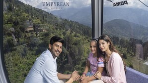 Una familia de tres sentada junto a una ventana con vista a un paisaje montañoso.
