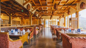 Un restaurante con vigas de madera, asientos acolchados y lámparas colgantes de mimbre.