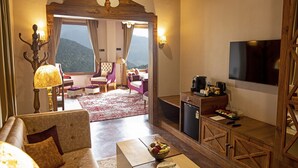 Una sala de estar acogedora con chimenea, asientos cómodos, una estación de café y un televisor grande.
