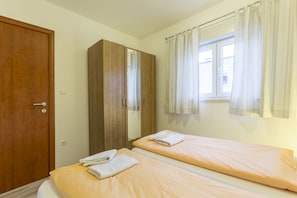 A bedroom with two beds, a wardrobe, and a window with curtains. - A2 - Spacious apt With the sea View & use of Pool (Podstrana)