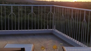 A balcony with a table set for two, featuring glasses with lemon slices and a small bowl of nuts.