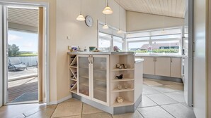 Eine moderne Küche mit integriertem Weinschrank, großen Fenstern und Pendelleuchten.