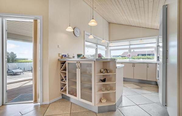 A modern kitchen with a built-in wine rack, large windows, and pendant lighting. - Beautiful home in Vinderup with sauna (Vinderup)