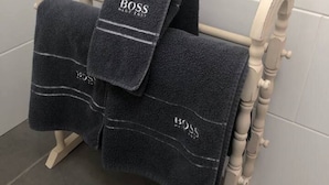 A towel rack with three towels, each labeled "BOSS." - 1-bed Sunny Studio Apartment in Tregony, Truro (Truro)