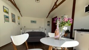 A dining area with a white table and chairs, a vase with flowers, and a ceiling light. - 1-bed Sunny Studio Apartment in Tregony, Truro (Truro)