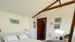 A bedroom with a bed, a chair, a nightstand, and a small table with a lamp and a plant. - 1-bed Sunny Studio Apartment in Tregony, Truro (Truro)