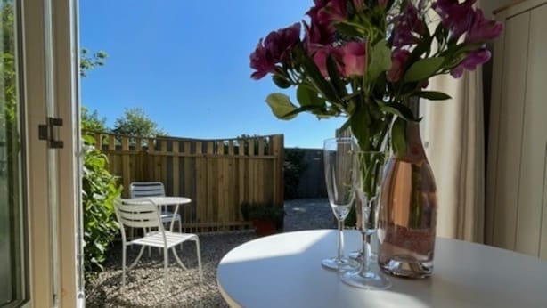 A patio with a white table, a vase with flowers, and two wine glasses. - 1-bed Sunny Studio Apartment in Tregony, Truro (Truro)