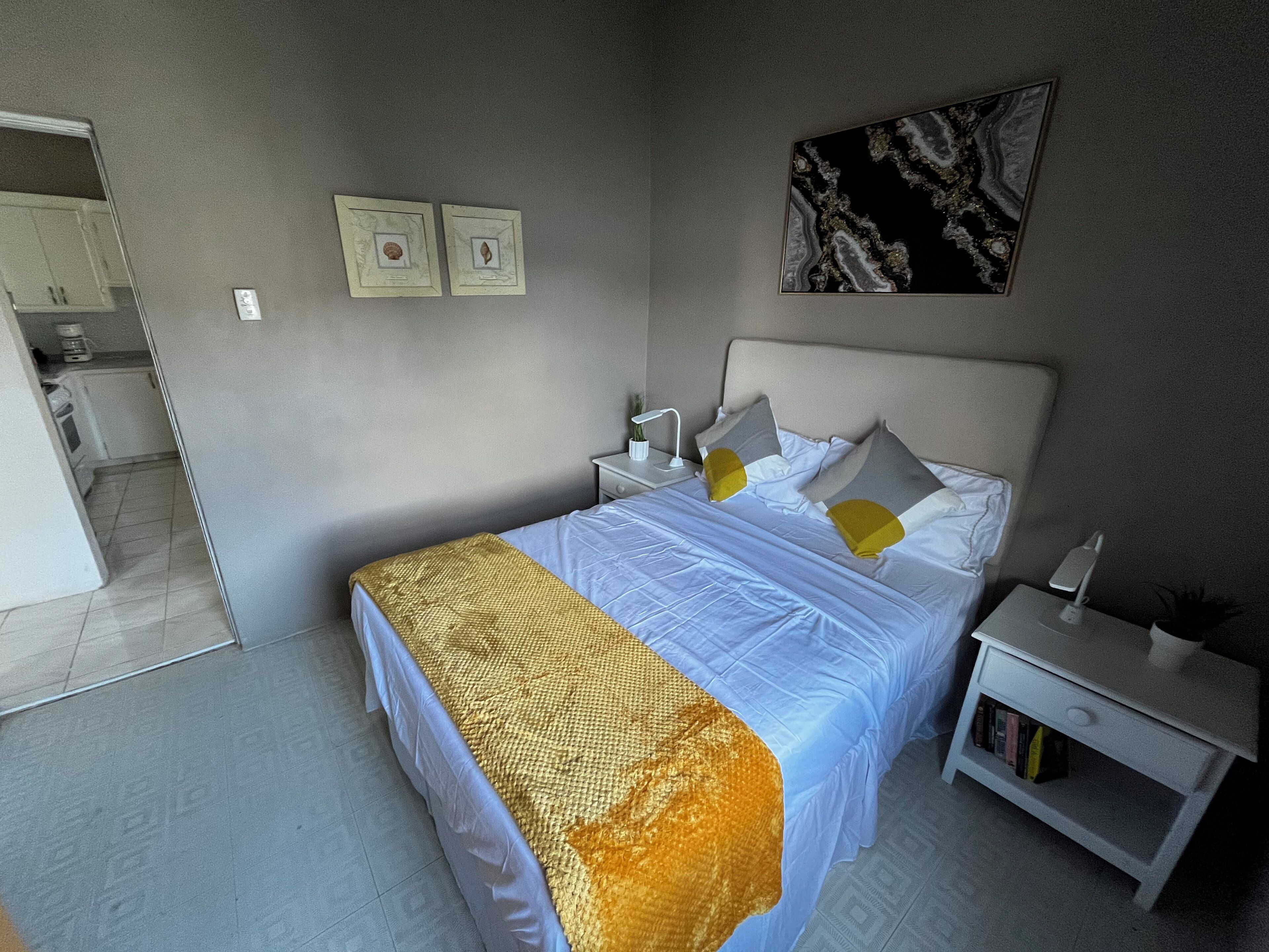 A bedroom with a bed, nightstands, a bedside table, a lamp, and a painting on the wall.