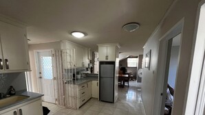 Una cocina con armarios blancos, un refrigerador y un comedor con mesa y sillas.