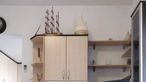 A modern kitchen with wooden cabinets, a built-in oven, and a microwave. There is a small ship model on top of the cabinets. - Apartments 4 You (Novalja)