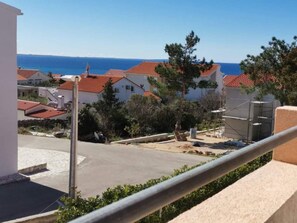 A residential area with houses, a clear view of the sea, and a paved road.