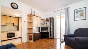 A compact living space with a kitchenette, a television, and a seating area. - Apartments 4 You (Novalja)