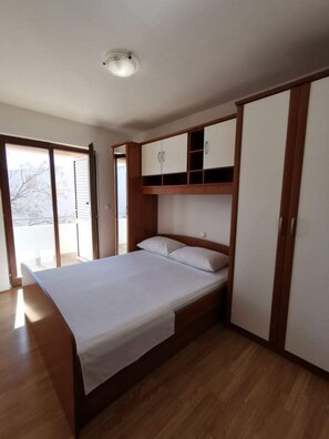 A bedroom with a bed, wooden wardrobe, and a ceiling light.