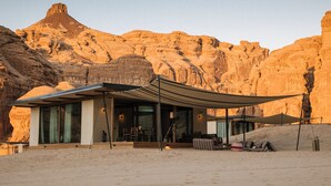 Un resort en el desierto con una zona de estar al aire libre techada, una piscina y vistas del paisaje rocoso circundante.