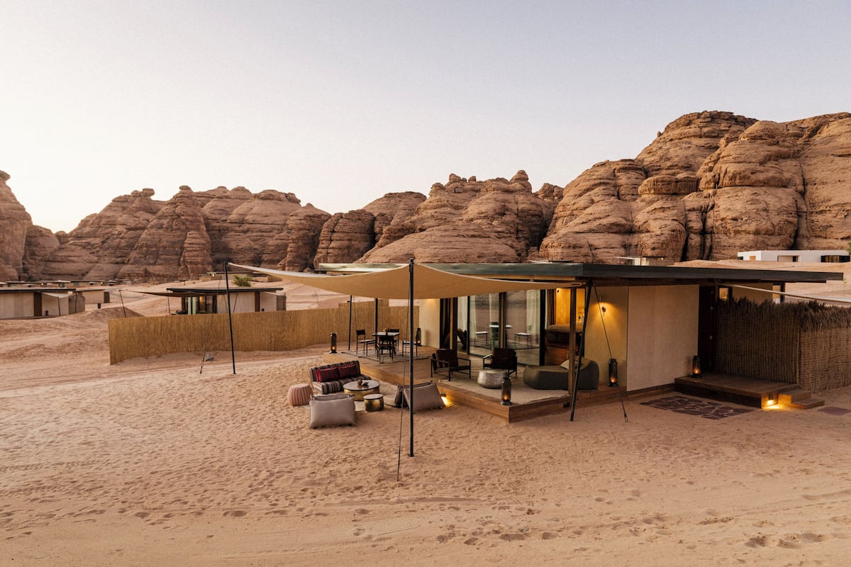 Un resort en el desierto con un área lounge moderna al aire libre, una piscina y vistas a montañas rocosas.