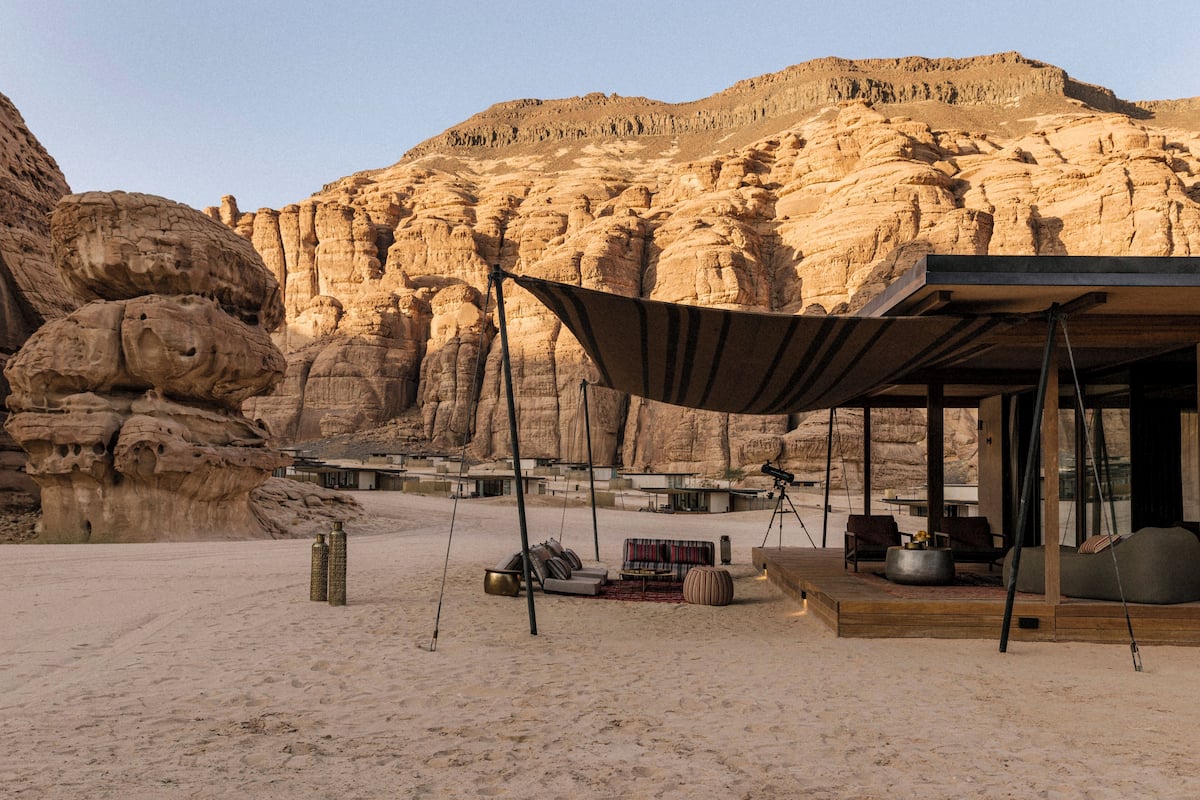 Un resort en el desierto con una zona de estar al aire libre techada, piscina y vistas a formaciones rocosas.