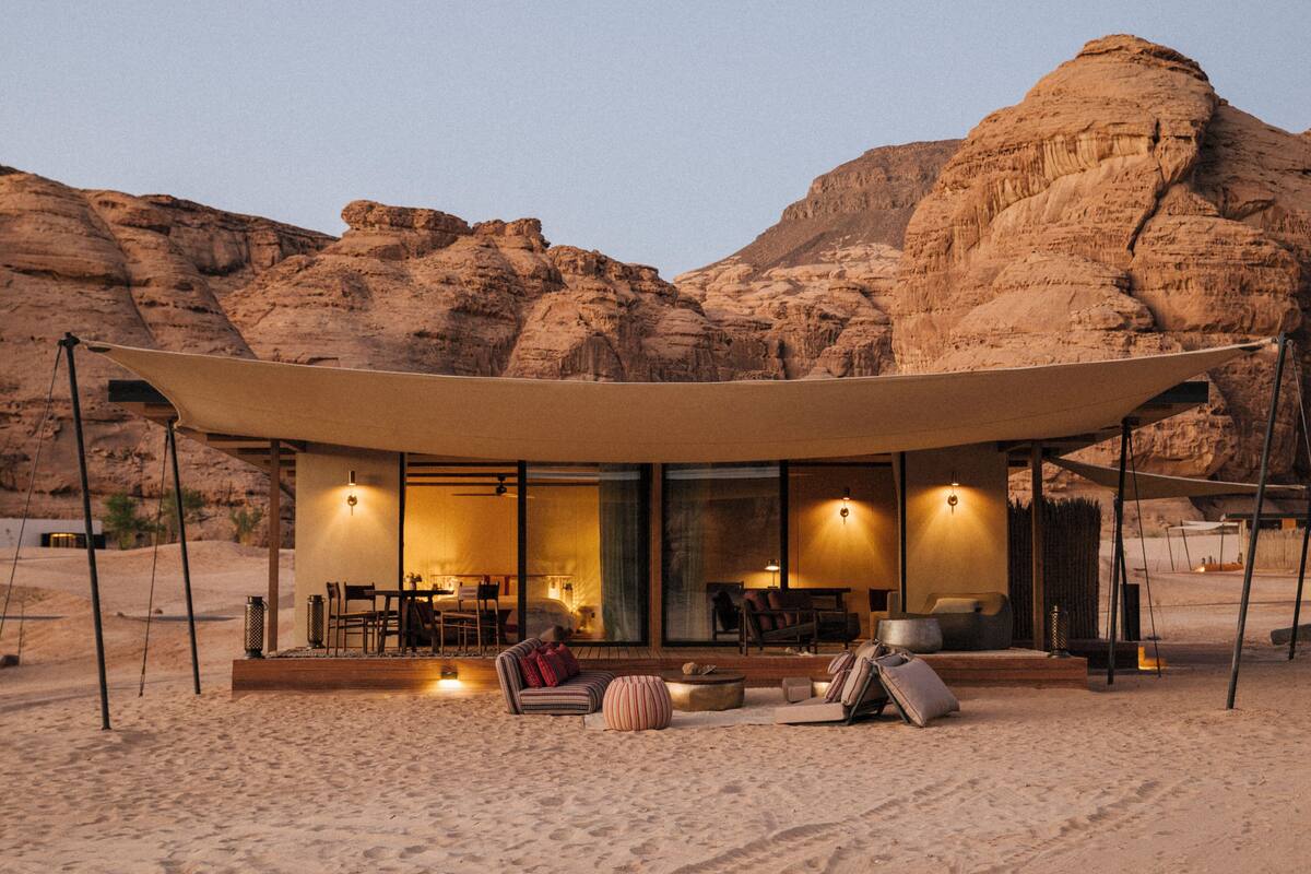 Un resort en el desierto con una zona de estar cubierta al aire libre, un espacio para comer y vistas del paisaje rocoso circundante.
