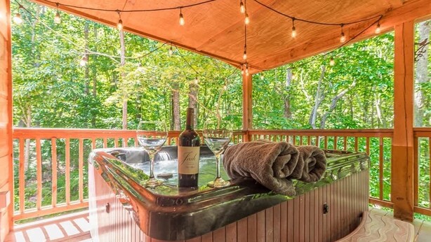 A hot tub with a bottle of wine and glasses, surrounded by wooden railings and a canopy. - THREE BEARS CABIN, PRIVATE MOUNTAIN GETAWAY (Sautee Nacoochee)