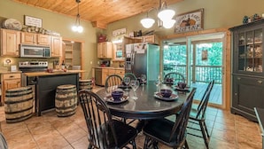A wooden interior with a dining area, kitchen, and a view through a glass door. - THREE BEARS CABIN, PRIVATE MOUNTAIN GETAWAY (Sautee Nacoochee)