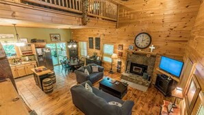 A cozy cabin interior with a dining area, sofas, a fireplace, and a TV. - THREE BEARS CABIN, PRIVATE MOUNTAIN GETAWAY (Sautee Nacoochee)