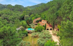 En villa omgivet af tæt skov, med en swimmingpool og en bro af sten.