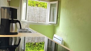 Una cocina con techo de madera, paredes verdes y ventana con vista a follaje.