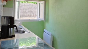 Cocina compacta con tragaluz, cafetera y ventana con vistas a la vegetación.