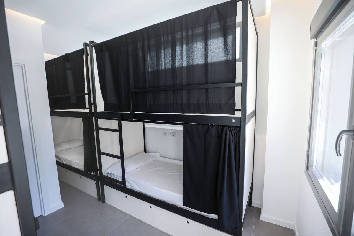 Habitación con literas, una escalera, una ventana y una puerta.