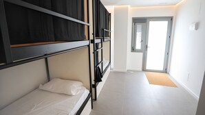 A modern hotel room with bunk beds, a door leading to a balcony, and a light-colored tiled floor. - Hostel MYD La Latina (Madrid)