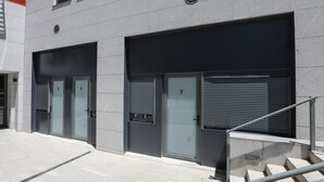A building with two garage doors, numbered 5 and 7, and a metal staircase leading up to a landing. - Hostel MYD La Latina (Madrid)