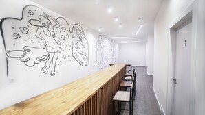 A modern hotel lobby with a long reception desk, wooden paneling, and abstract wall art. - Hostel MYD La Latina (Madrid)