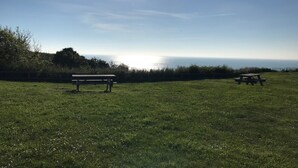 Un campo con mesas de picnic y vista al mar.