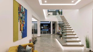 Un interior moderno con una escalera, un sofá y un cuadro abstracto de colores vivos.