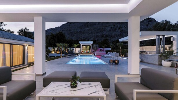 Zona de piscina exterior moderna con asientos y vistas a un paisaje montañoso.