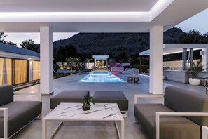 Zona de piscina exterior moderna con asientos y vistas a un paisaje montañoso.