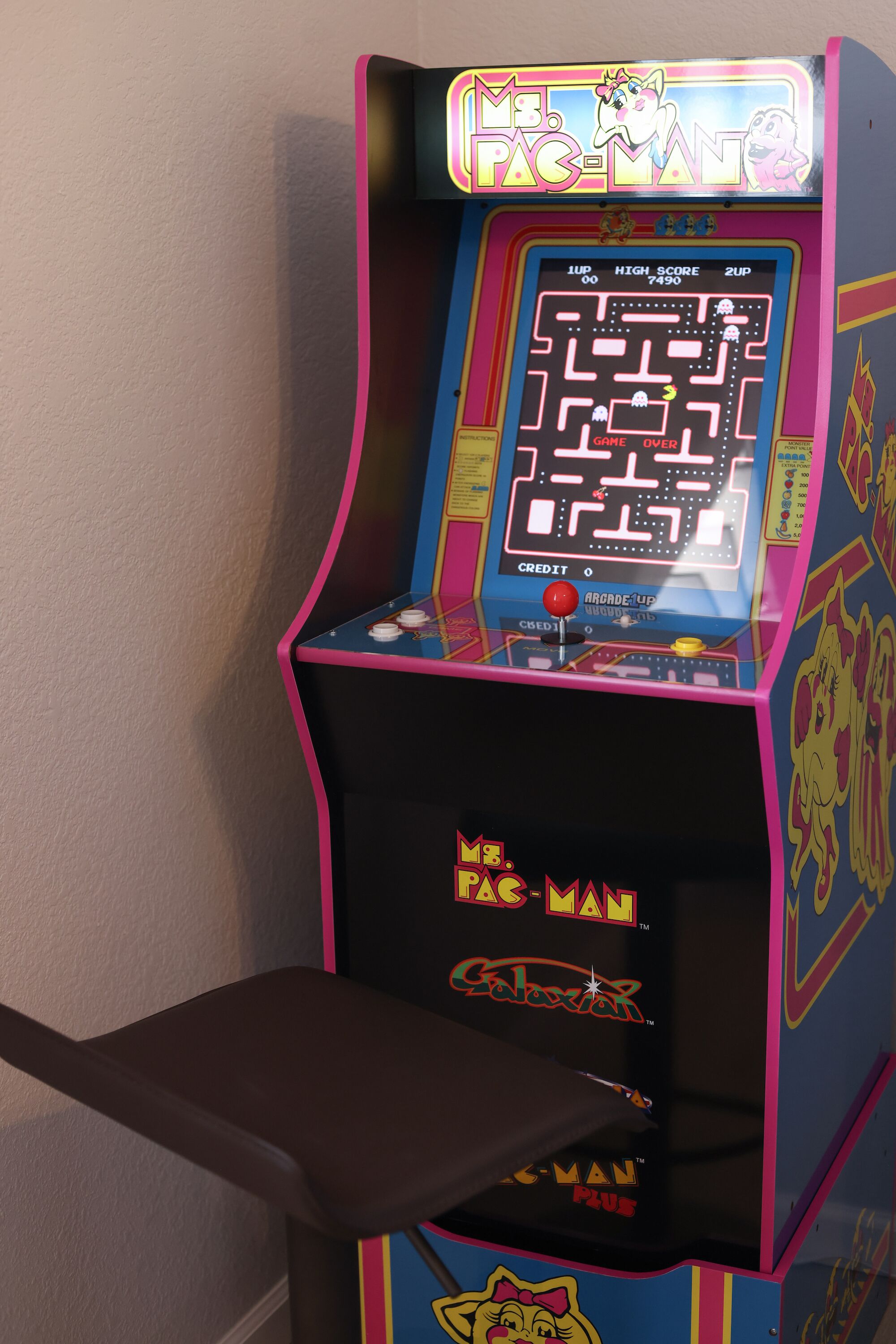 A vintage Pac-Man arcade machine with a neon sign, a joystick, and a coin slot.