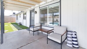 Un espacio de patio cubierto con piscina, mobiliario exterior y vista a la piscina.