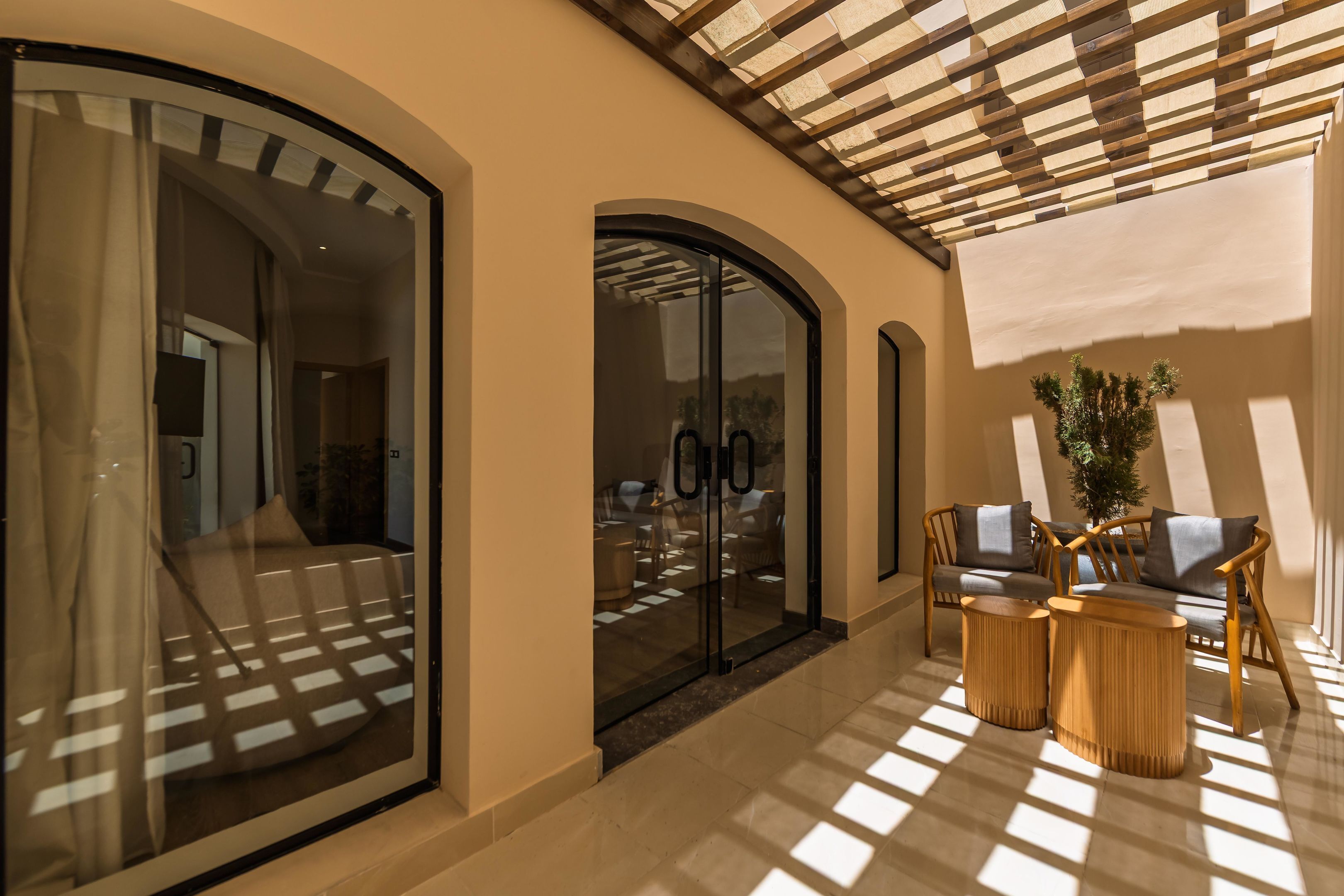 Un interior il·luminat pel sol, amb zona d'estar, una porta de vidre i una estructura de sostre de fusta.