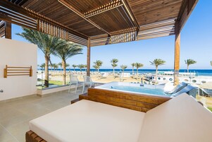 Una habitación con techo de madera, una cama, vista a la playa y zona de piscina.