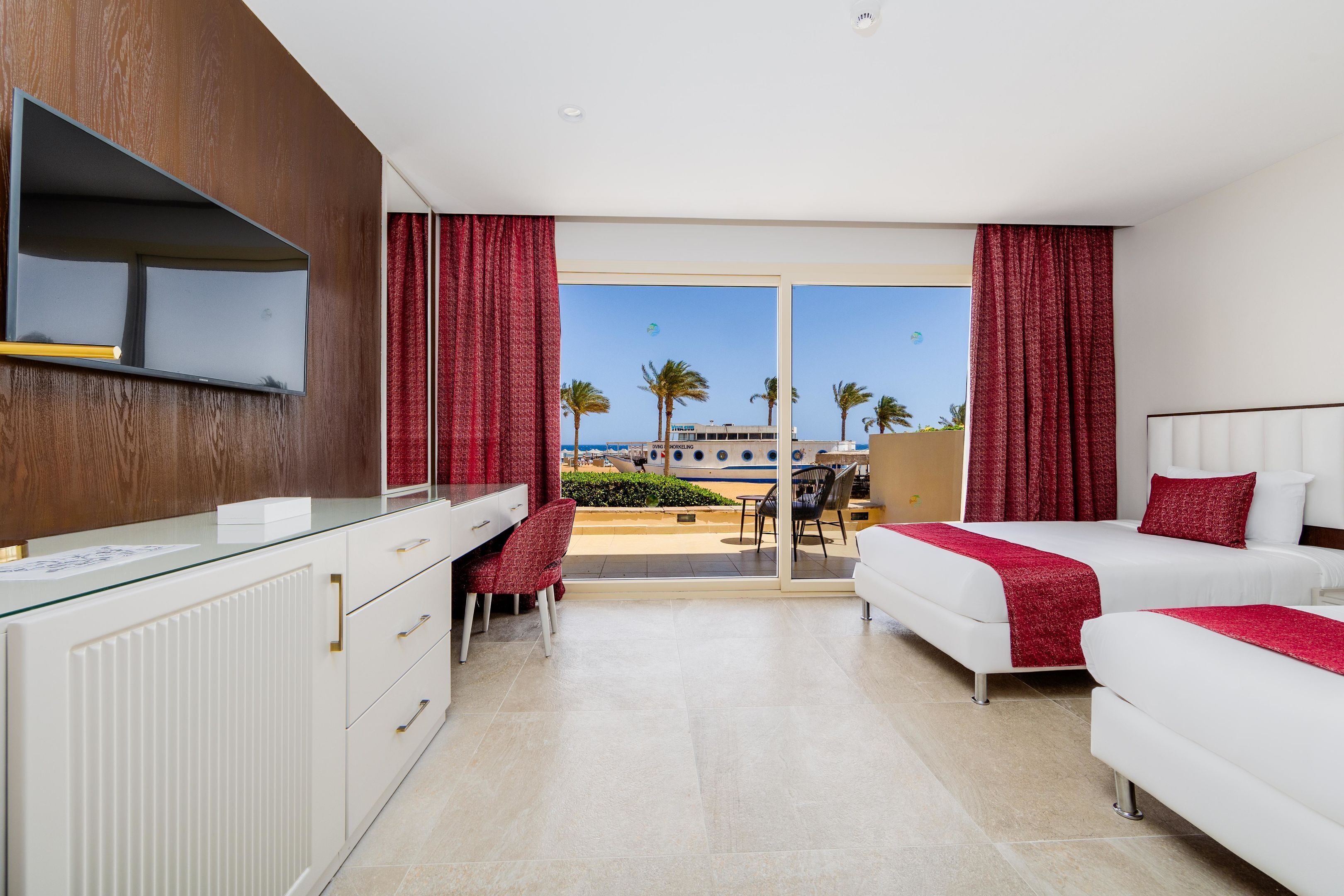 Une chambre d’hôtel avec un lit, un bureau et une vue sur la plage.