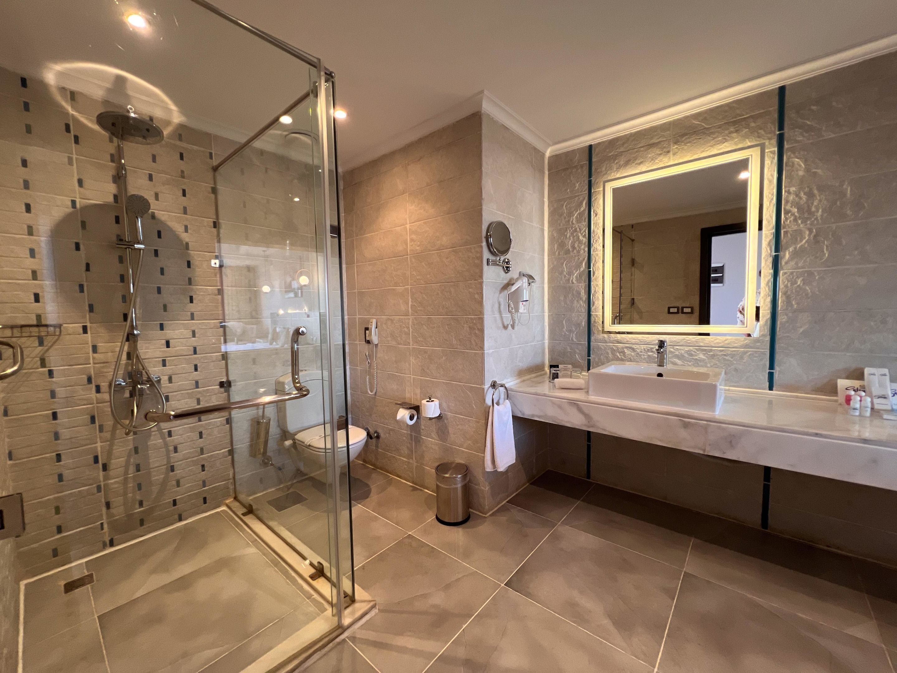 Un bagno moderno con cabina doccia in vetro, uno specchio grande e un mobile lavabo.